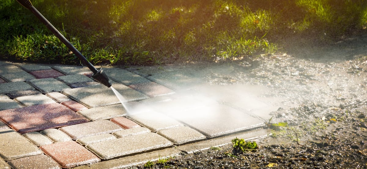 Filthy block pavement being restored with a high-pressure washer