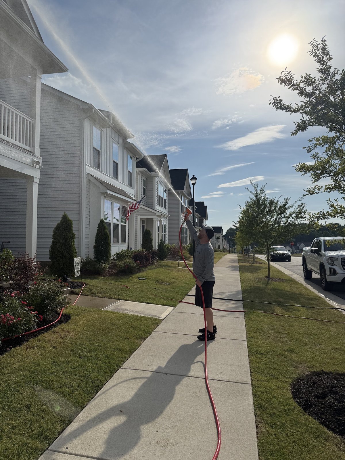 Person jumping rope on sidewalk in residential neighborhood with white two-story houses on a sunny day