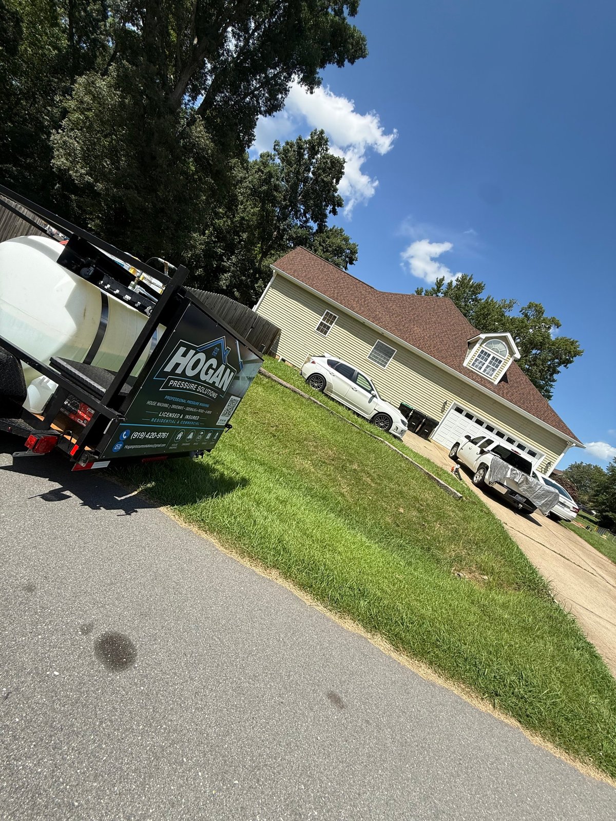 Delivery truck parked in front of suburban home with driveway, green lawn, and clear blue sky